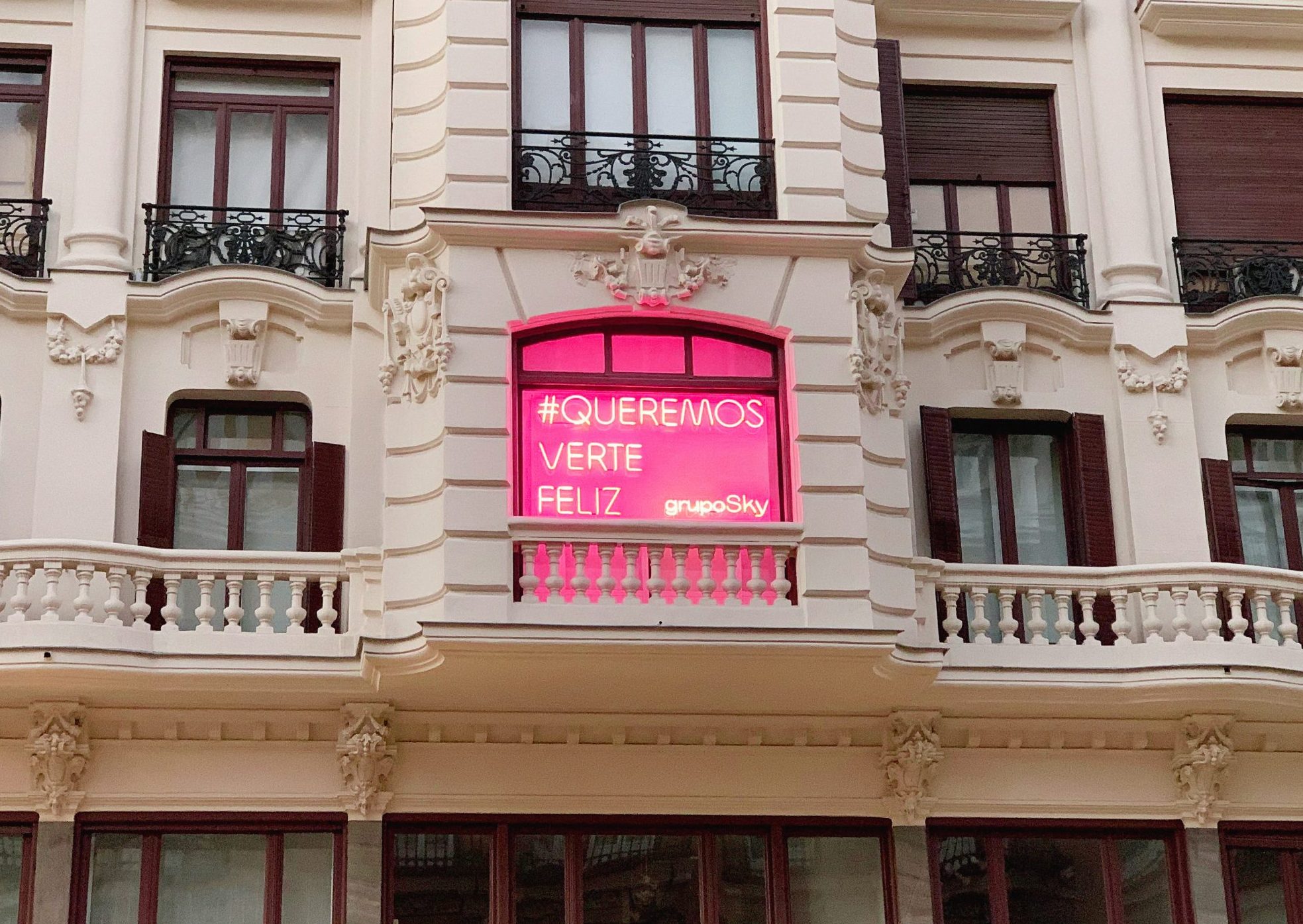 Neon rosa en exterior de oficina queremos verte feliz